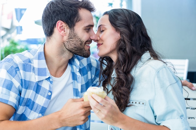 Casal se beijando enquanto segura cupcakes