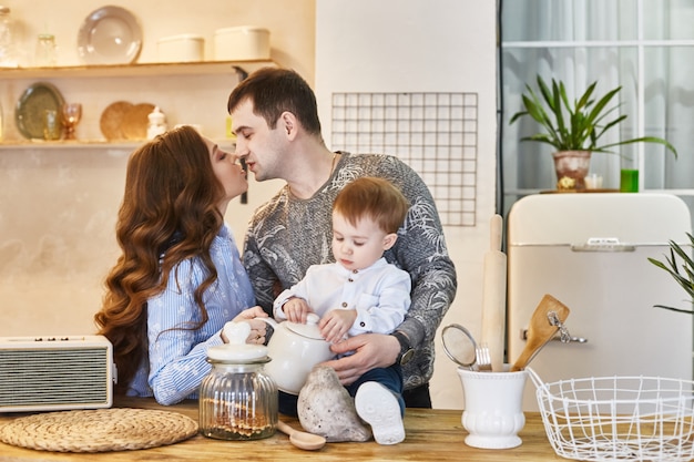 Casal se beijando na cozinha com seu filho