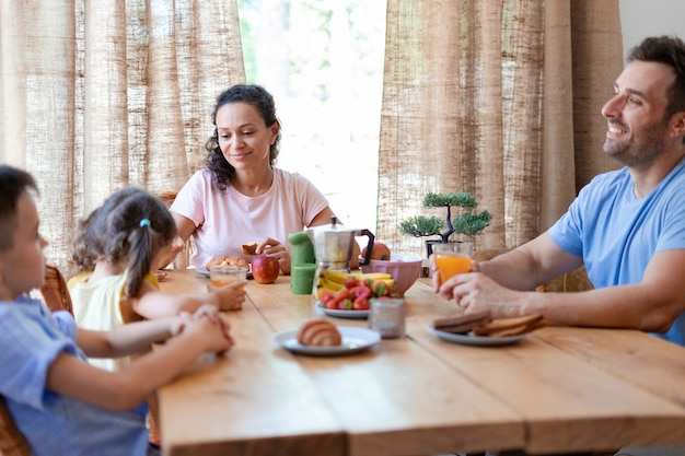 Foto casal se comunica com seus filhos durante o café da manhã discutindo planos para este dia ensolarado