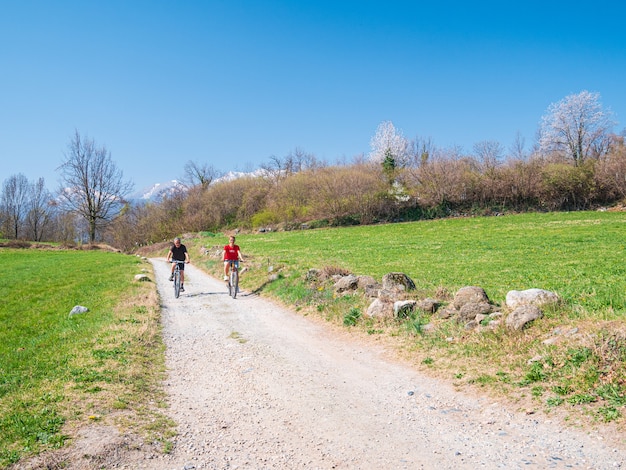 casal se divertindo andando de bicicleta de montanha em estrada de terra em um dia ensolarado