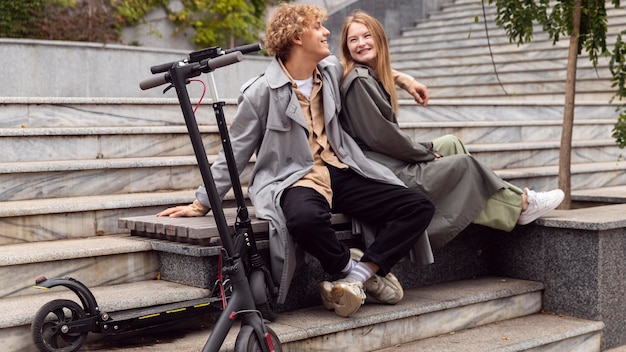 Foto casal se divertindo ao ar livre ao lado de uma scooter elétrica