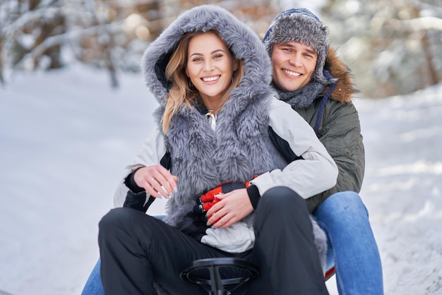 Casal se divertindo com o trenó na neve na neve do inverno. Foto de alta qualidade