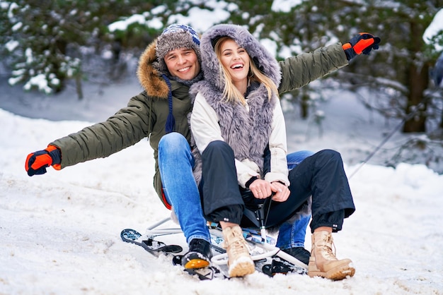 Casal se divertindo com o trenó na neve na neve do inverno. Foto de alta qualidade