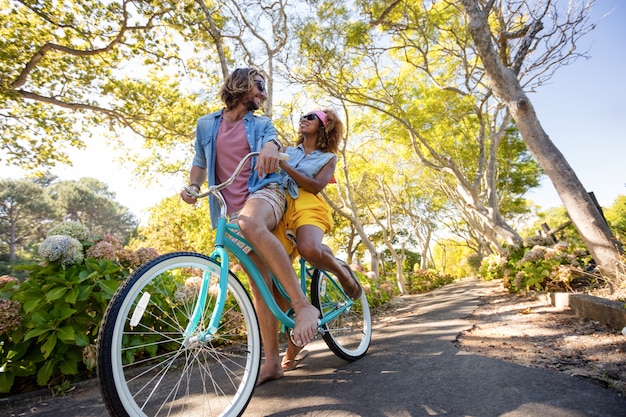 Foto casal se divertindo enquanto andava de bicicleta no parque