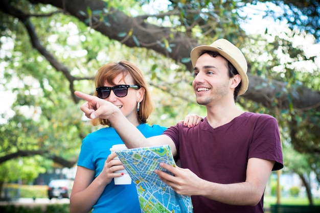 Casal segurando o mapa nas mãos e viajando juntos.