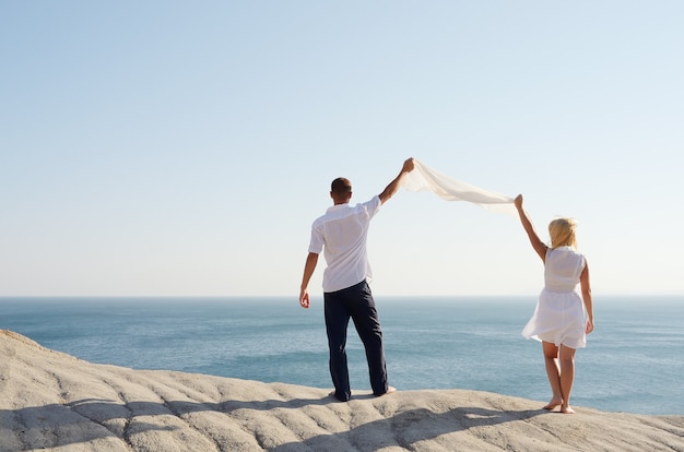 Foto casal segurando um lenço branco e olhando para o mar