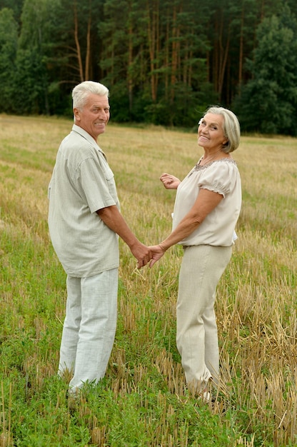 Casal sênior andando no campo de verão durante as férias