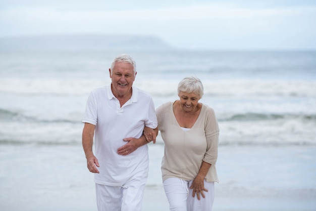 Casal sênior caminhando juntos na praia