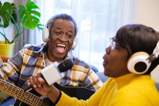 Casal sênior cantando músicas de karaokê e tocando violão em casa Conceito de estilo de vida música envelhecimento