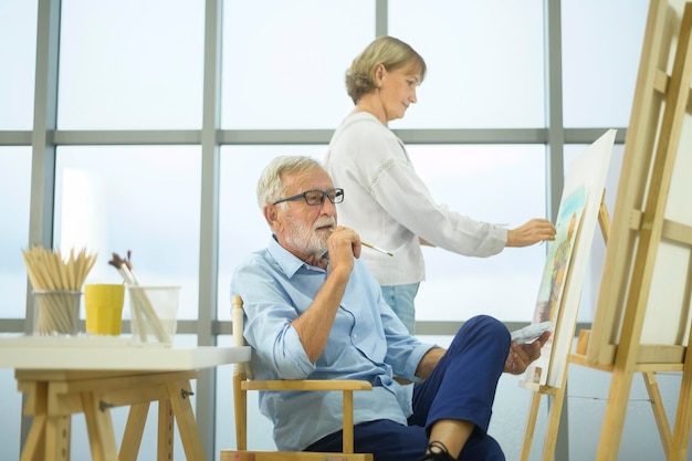 Casal sênior caucasiano pintando e relaxando em casa