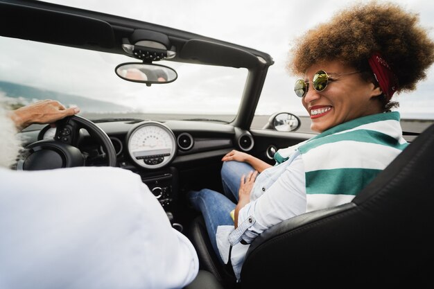 Casal sênior da moda dentro de um carro conversível no feriado - foco no rosto da mulher