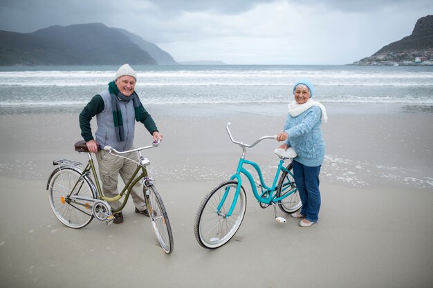 Casal sênior dançando com bicicletas na praia