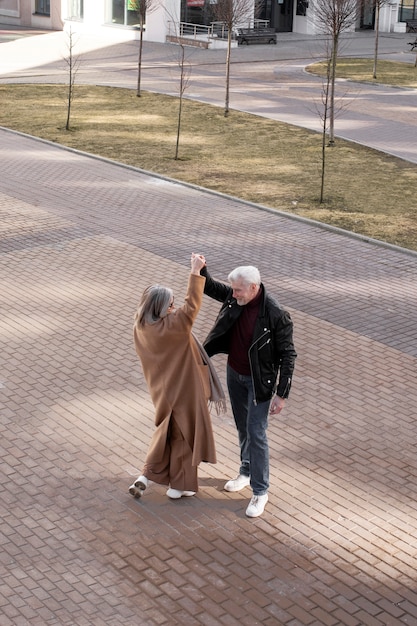 Foto casal sênior de tiro completo dançando ao ar livre