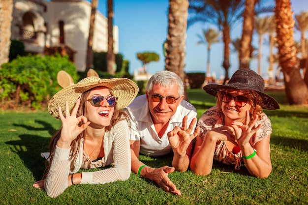 Foto casal sênior deitado na grama com a filha adulta no hotel pessoas felizes aproveitando as férias de verão no egito valores familiares