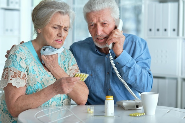 Casal sênior doente ligando para o médico