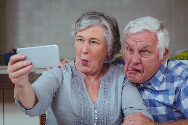 Casal sênior fazendo caretas enquanto estiver a tomar selfie