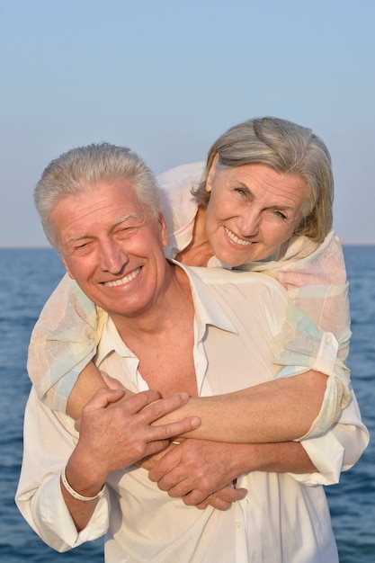 Casal sênior fofo e feliz no mar ao pôr do sol