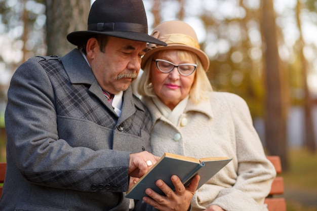 Casal sênior lendo um livro juntos no parque outono