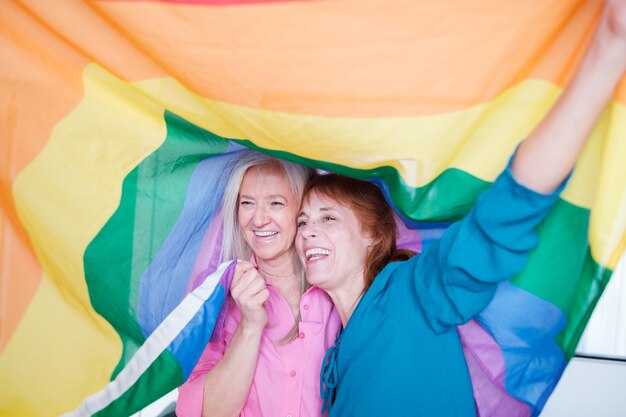 Casal sênior lgtbi sorrindo enquanto se abraçava com uma bandeira lgtbi Conceito orgulho arco-íris casal lgtbi