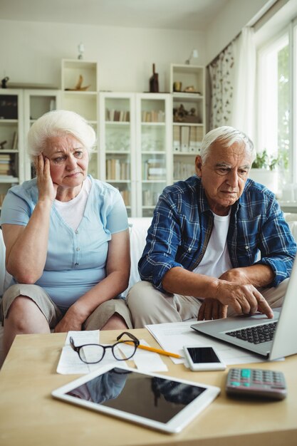 Casal sênior preocupado usando laptop