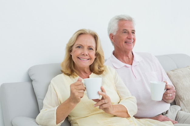 Casal sênior relaxado com copos de café em casa