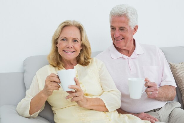 Casal sênior relaxado com copos de café em casa