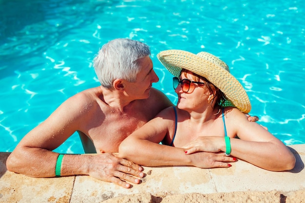 Casal sênior relaxando na piscina Pessoas felizes aproveitando as férias de verão Tudo incluído