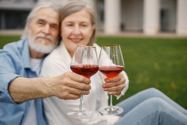 Casal sênior segurando dois copos com vinho na frente de si