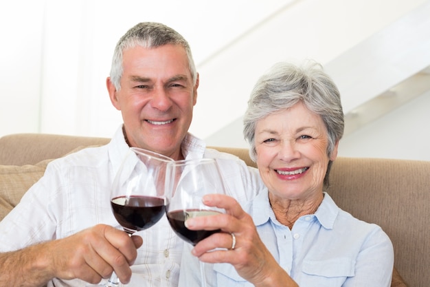 Casal sênior sentado no sofá com vinho tinto