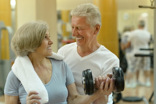 Casal sênior sorridente ativo se exercitando na academia