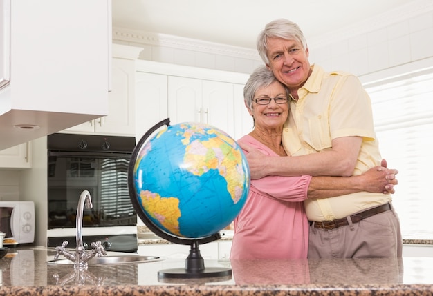 Foto casal sênior sorrindo para a câmera junto com o globo