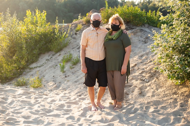 Casal sênior usando máscara médica para proteger do coronavírus fora na natureza do verão, quarentena de coronavírus