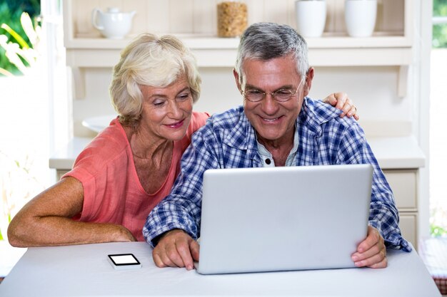 Casal sênior usando o laptop em casa