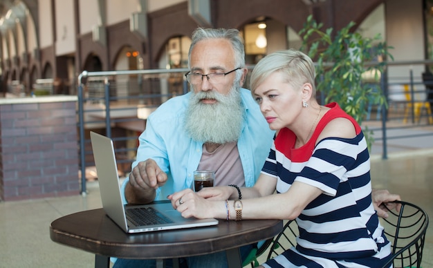 Casal sênior usando o laptop juntos no café