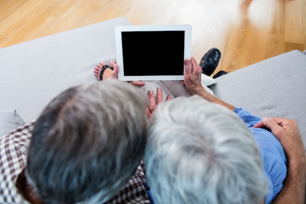 Casal sênior usando um tablet digital no sofá