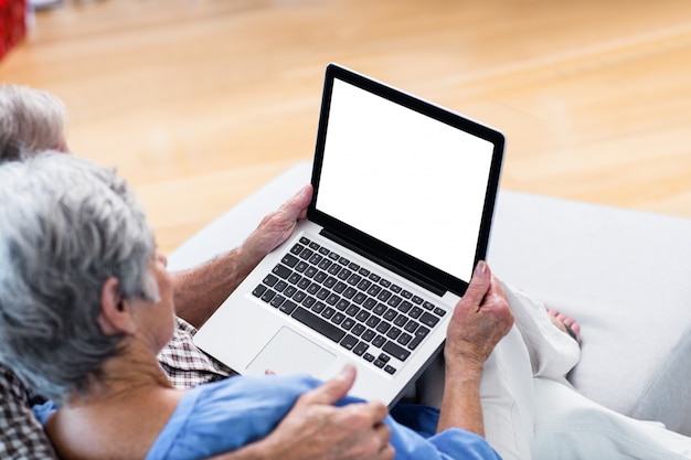 Casal sênior usando um tablet digital no sofá