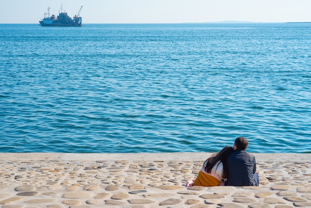 Casal senta na praia pelo mar Cáspio em Baku