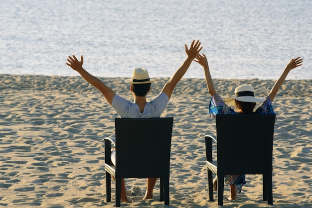 Foto casal sentado em cadeiras na praia