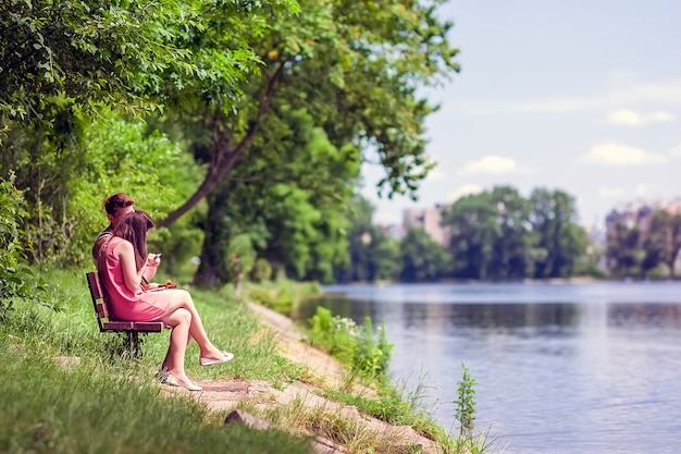 Casal sentado em um banco ao lado de um lago em um dia ensolarado de verão