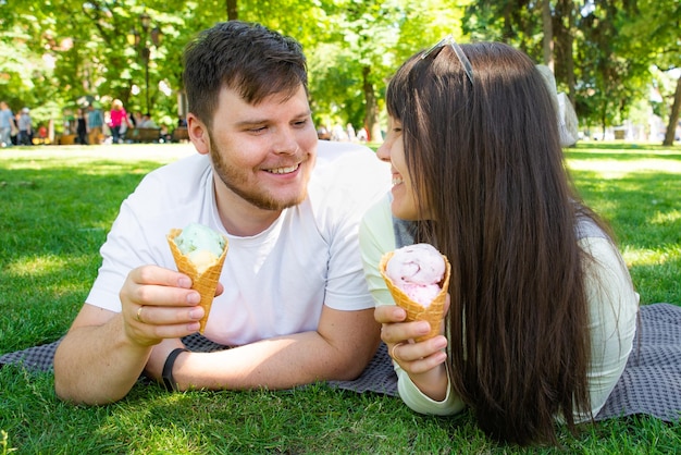 casal sentado em um cobertor e comendo sorvete no parque da cidade em um dia de verão