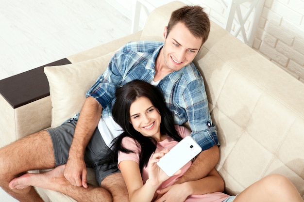 Casal sentado em um sofá e usando um telefone