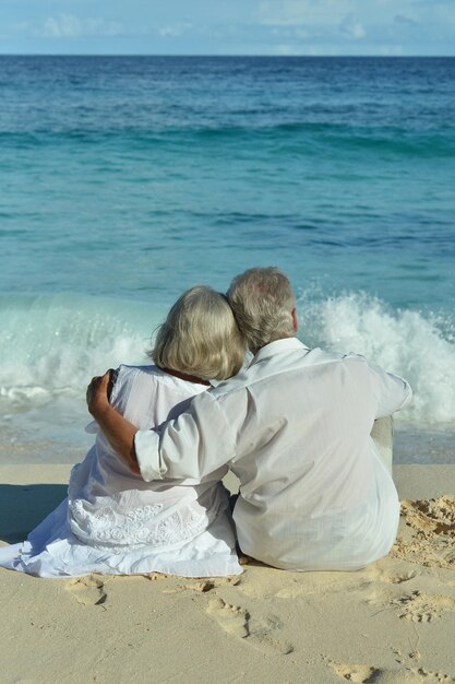 Foto casal sentado na praia tropical