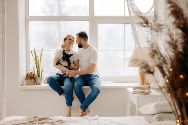 Casal sentado no peitoril da janela com um cachorro