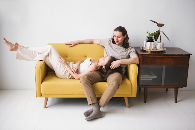 Foto casal sentado no sofá amarelo na sala homem e mulher apaixonados em um novo apartamento conforto doméstico