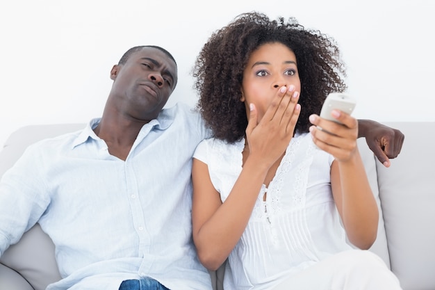 Casal sentado no sofá, assistindo tv