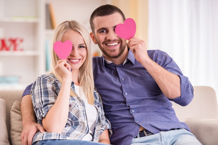 Foto casal sentado no sofá em casa, olha para a câmera.