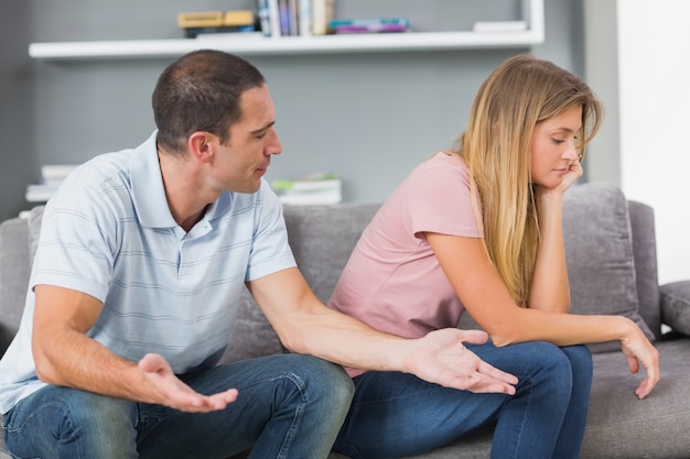 Casal sentado no sofá tendo um argumento