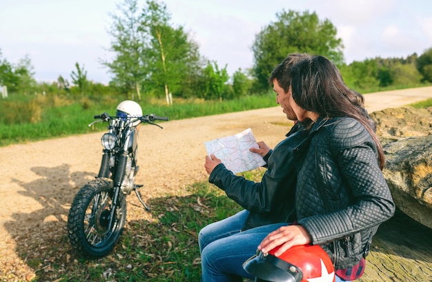 Casal sentado olhando para um mapa com motocicleta