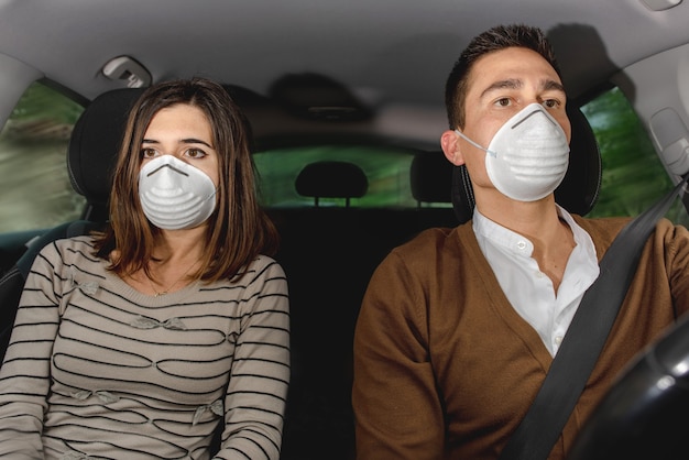 Casal sério dentro do carro, usando máscara facial. proteção da saúde, segurança e conceito de pandemia. dirigindo durante a pandemia de coronavírus.