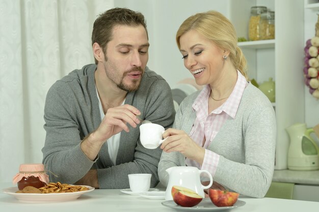 Casal sorridente à mesa com café e comida